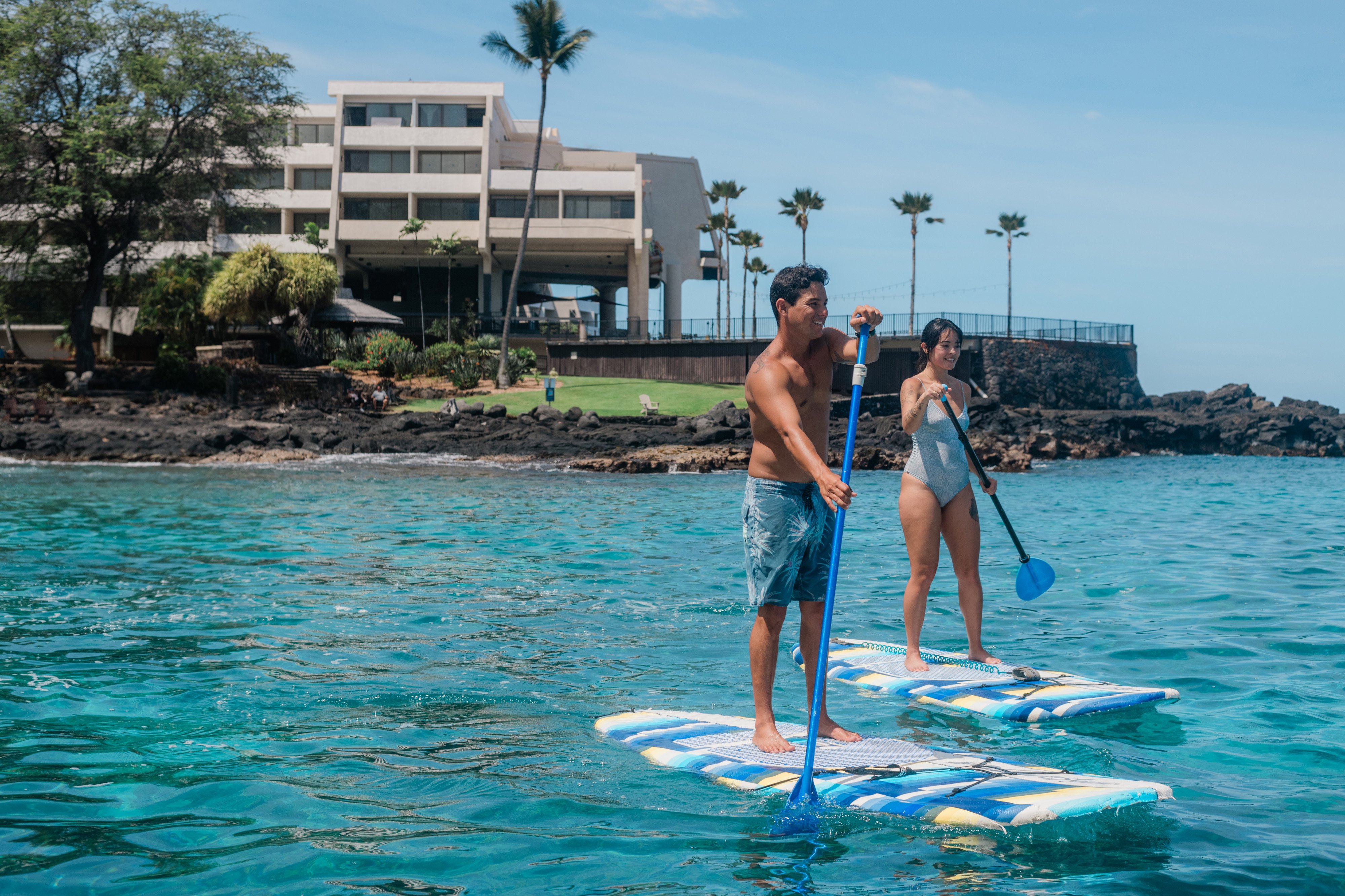 A couple stand up paddle boarding in Keauhou Bay