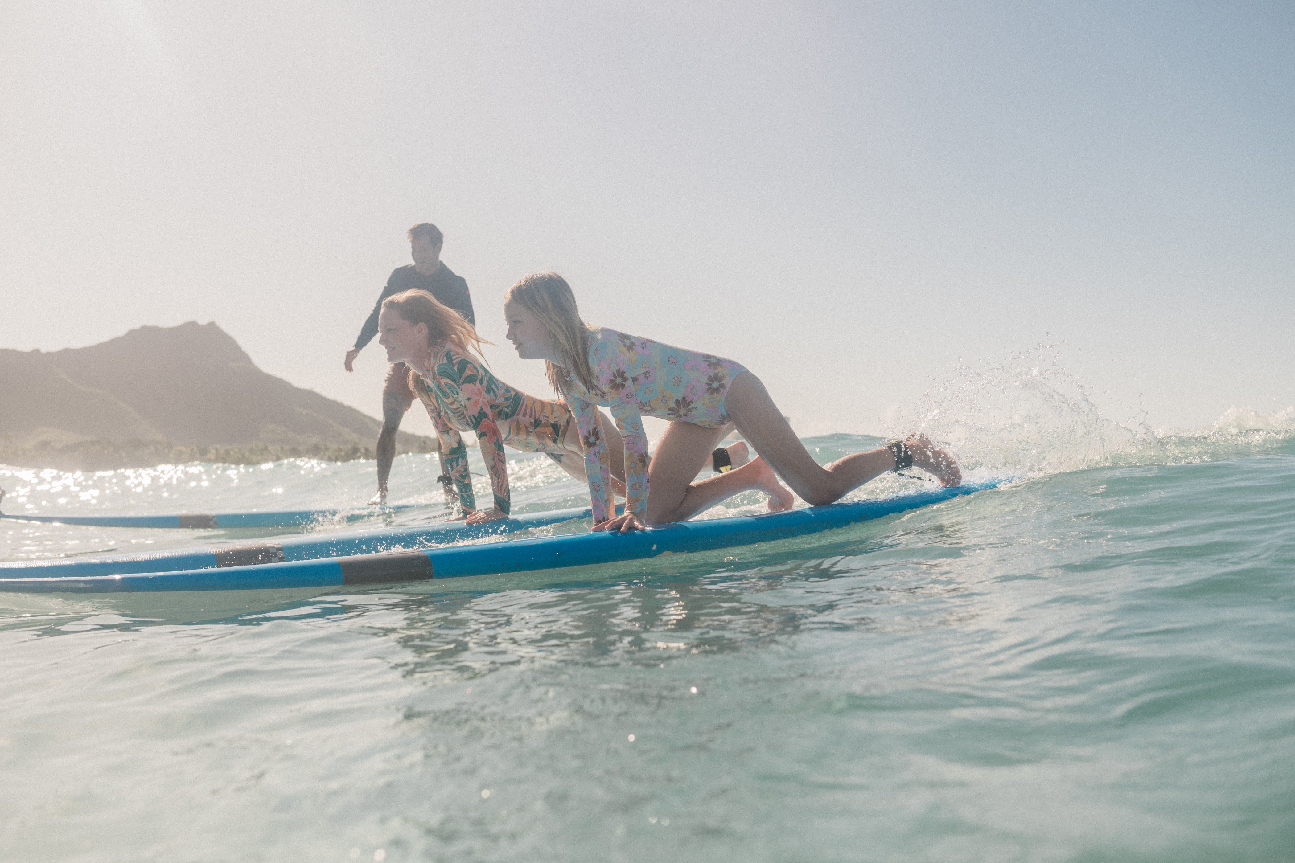 Two girls learning to surf on a wave in Waikiki